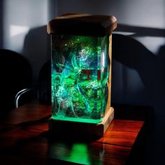 an aquarium is sitting on top of a wooden table in front of a dark wall