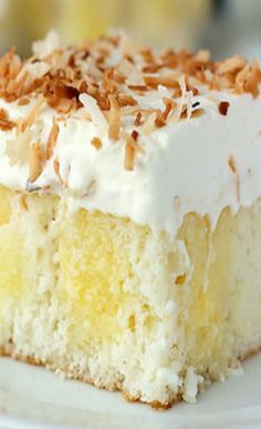 a piece of cake with white frosting and toasted coconut on top is sitting on a plate