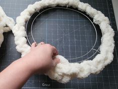 someone is making a wreath out of fake sheep's wool and yarn with scissors