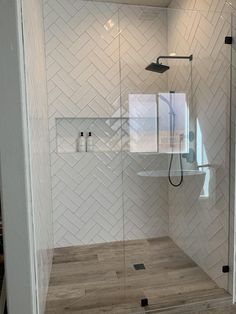 a walk in shower sitting inside of a bathroom next to a wooden floor and white walls