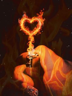 a hand holding a lighter with a heart shaped object on it's tip and flames in the background