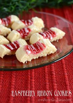 raspberry ribbon cookies on a glass plate with holly sprig in the background