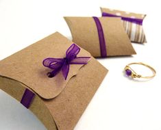 two pieces of brown paper with purple ribbon tied around them and one piece of gold ring