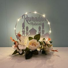 an illuminated sign with flowers in front of it that says ramaad mubarak