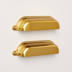 two shiny gold door handles on a white background