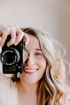 a smiling woman holding up a camera to take a selfie with it's lens