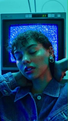 a woman with her eyes closed in front of an old television set and the screen has blue lights on it