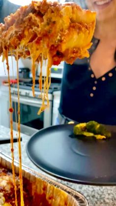 a woman is holding up a piece of deep dish pizza with cheese and sauce on it