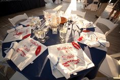 the table is set with white and red napkins, wine glasses, and personalized t - shirts