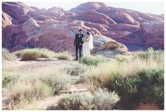 a bride and groom standing in the desert