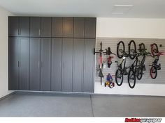 there are many bikes hanging on the wall in this bike storage room with gray cabinets