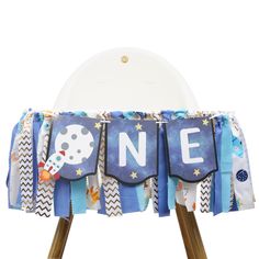 a blue and white table cloth with the word one on it's front, sitting on top of two wooden legs