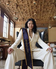 a woman sitting in a chair wearing a sash