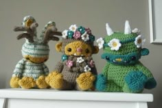 three crocheted stuffed animals sitting on top of a white shelf next to each other