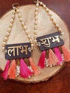 two tasseled earrings with the word'bhoj'written in english on them