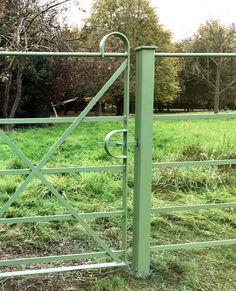 a green gate in the middle of a grassy field