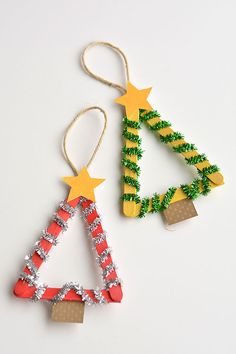 two christmas trees made out of popsicle sticks on a white surface with stars and tinsel