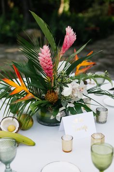 a table topped with lots of flowers and greenery next to glasses filled with water