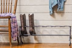 a pair of cowboy boots are hanging on a rack next to a chair and coat rack