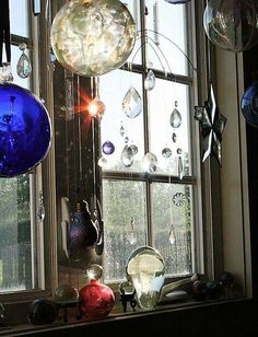 several glass ornaments are hanging in front of a window with sunlight coming through the windows