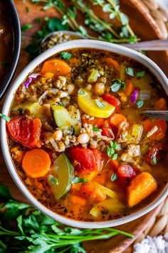 a bowl of soup with carrots, zucchini and other vegetables