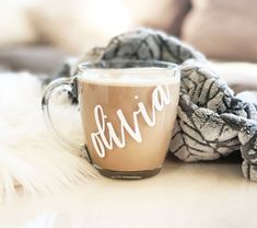 a cup of coffee sitting on top of a white table next to a pile of blankets