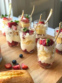 desserts in glass jars with strawberries, blueberries and raspberries on a cutting board