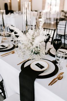 the table is set with black and white plates, silverware, and centerpieces