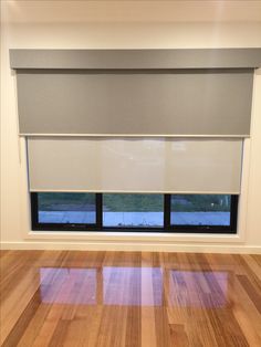 an empty room with hardwood floors and a window that has blinds on the windowsill