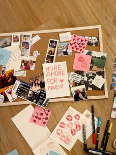 a cork board covered in pictures and writing on it next to pens, markers and paper