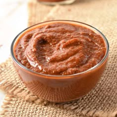 a small glass bowl filled with sauce on top of a burlap table cloth