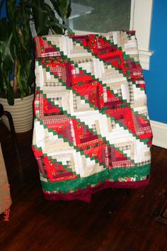 a quilted blanket sitting on top of a wooden floor next to a potted plant