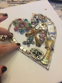 a woman's hand is holding onto a piece of art made out of jewelry