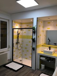 a bathroom with yellow and white tiles on the walls, shower stall and sink area