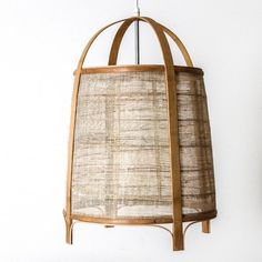 a lamp hanging from the ceiling with a wooden frame and woven shade on it's side