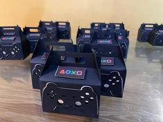 several black video game controllers sitting on top of a wooden table next to each other