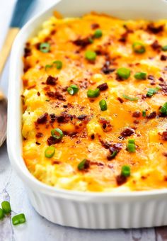 a casserole dish with cheese, green onions and seasoning in it on a table