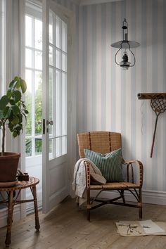 a living room with a chair, table and potted plant on the floor next to an open door