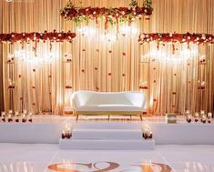 a white couch sitting on top of a floor next to a stage covered in flowers