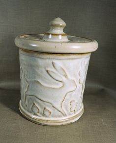 This handmade storage jar  is thrown by hand on  the wheel and decorated  with a sprigged rabbit , clover and oak leaf motif.  Satin White color glaze breaking to brown where thin with off-white interior.  Glazes are lead-free and food safe.  Red Stoneware Clay is locally mined California.   Vanity Jar is approximately 4.5" high and 4"diameter.  Each item is made by hand here in our Igo, CA studio Ceramic Mushrooms Pottery, Mushrooms Pottery, Ceramic Mushrooms, Carved Pottery, Ceramic Jar, Jar Storage, Leaf Motif, Color Glaze, Ceramic Jars