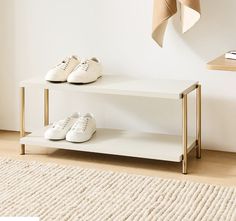 two pairs of white shoes are sitting on a shelf in front of a beige rug