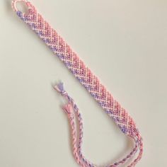 a pink and purple braided cord on a white surface with a hook in the middle