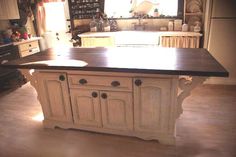 a large kitchen island in the middle of a room with an oven and refrigerator behind it