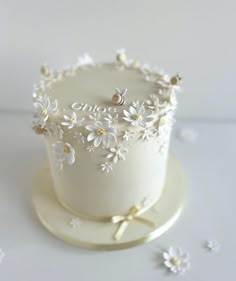 a white wedding cake with flowers and pearls on the top is sitting on a plate