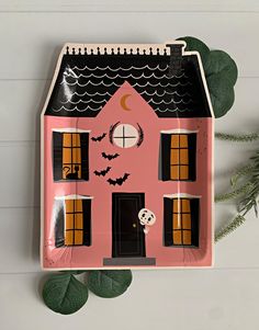 a pink and black house shaped tray with bats on the roof, windows, and door