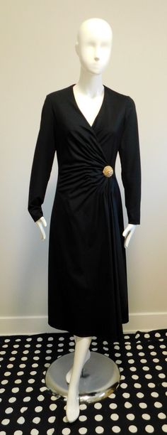 Black matte jersey lined wrap dress Long sleeves Secured with hook, tie and snap Embellished with a sewn on gold tone brooch with rhinestones  Labeled - Majestic  100% Polyester  Union Label  Please scroll through photos for measurements Fitted Evening Dress With Gold Buttons, Elegant Fitted Dresses With Gold Buttons, Elegant Evening Dresses With Gold Buttons, Elegant Party Dresses With Gold Buttons, Formal Fitted Dress With Gold Buttons, Black Double-breasted Button Fastening Evening Dress, Wrap Dress Long Sleeve, Velvet Coat, Gorgeous Fabrics