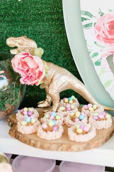 there is a dinosaur cake and cupcakes on the table next to each other