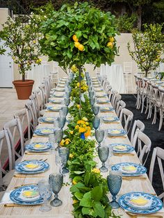 a long table set with blue and white plates, flowers and greenery on it