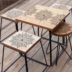 three wooden tables sitting on top of a wooden floor next to each other with designs painted on them