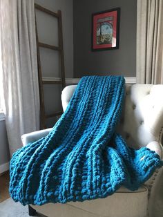 a couch with a blue blanket on top of it next to a chair and window